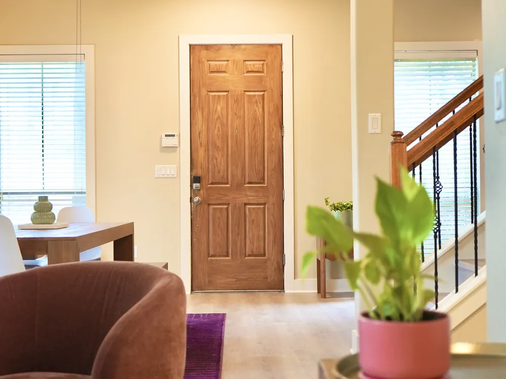 The entryway and staircase inside Empowered Treatment's transitional housing, with a wooden front door and plants