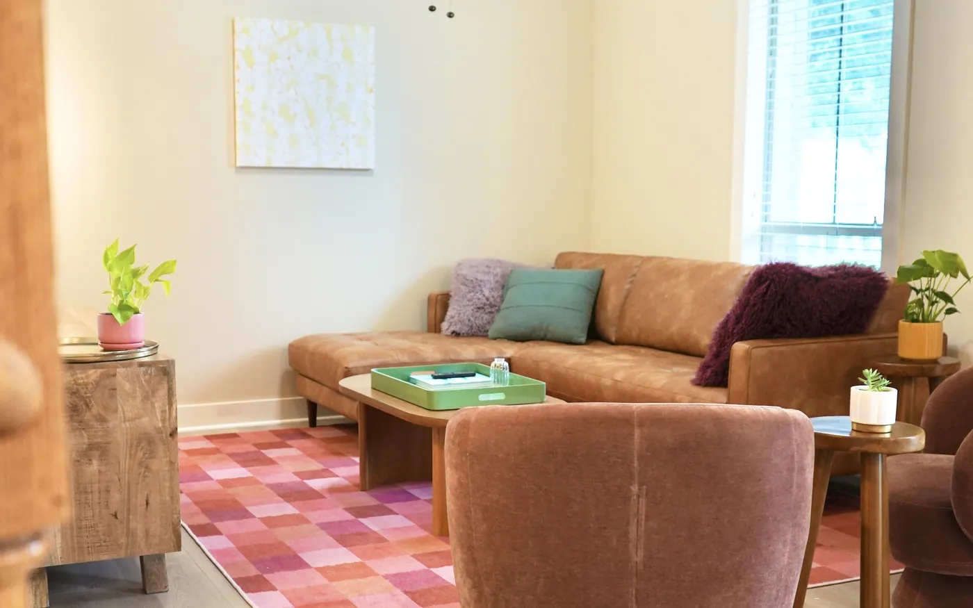 The shared living room at Empowered Treatment's transitional housing in Austin, with a leather sofa, soft chairs, and plants