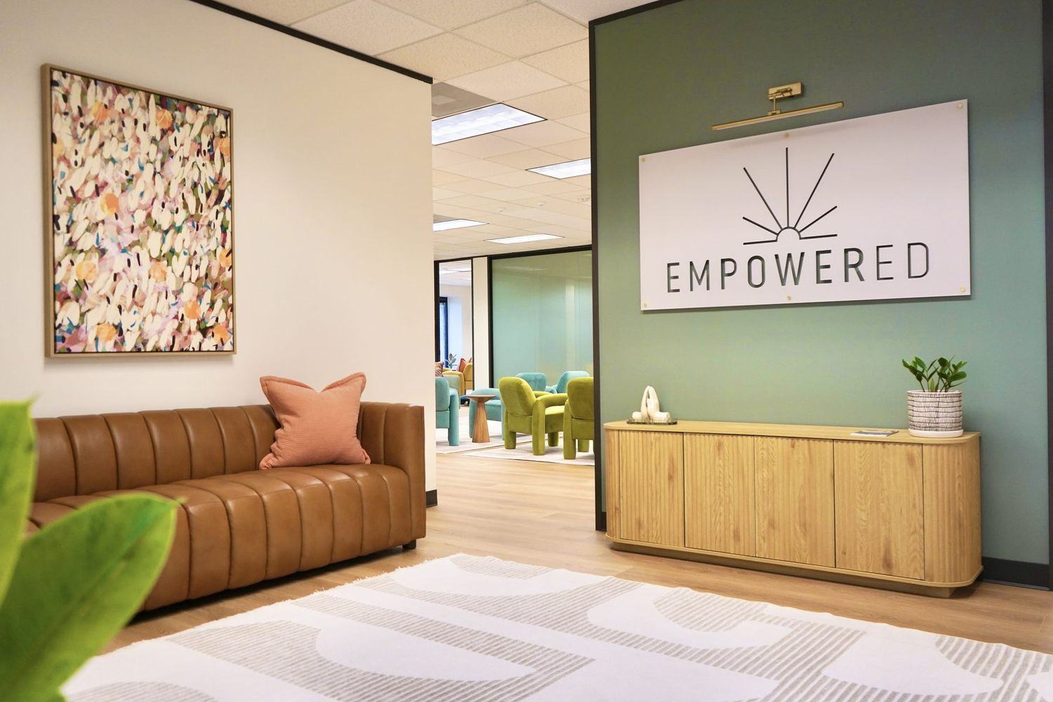 Reception at Empowered Treatment in Northwest Austin, with soft seating and the Empowered wordmark on a deep green wall