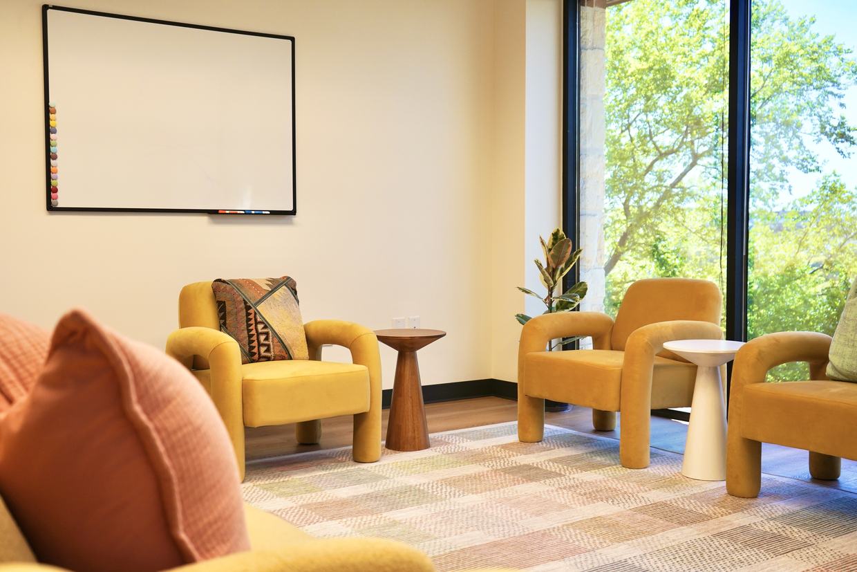 A group room at Empowered Treatment in Austin, with armchairs arranged in a circle beneath tall windows