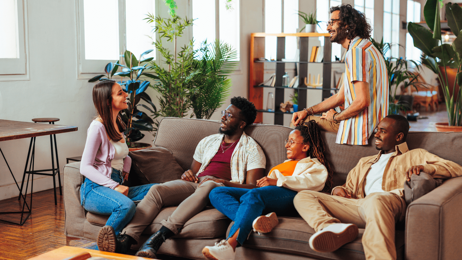 A diverse group of people talking indoors on a couch.