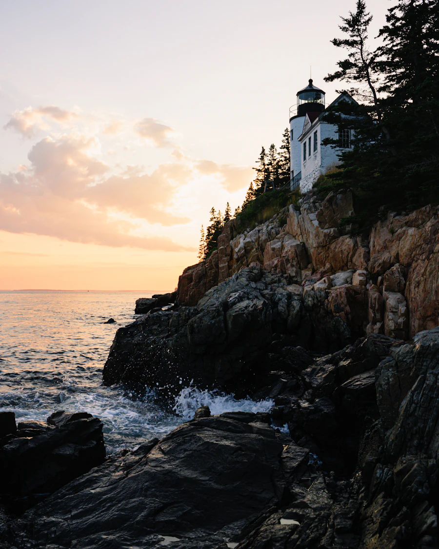 Rocky cliffs and a lighthouse at sunset in Acadia National Park, Maine